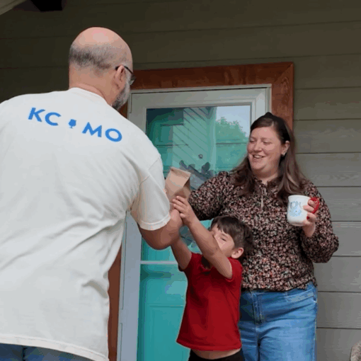 image of a man handing a bag of coffee beans to a mother and young boy on their front porch