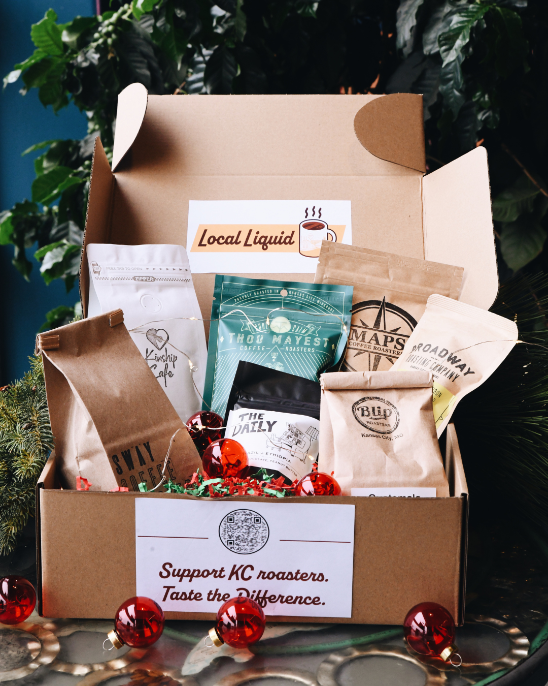 box of a variety of sample bags of coffee beans from kc local roasters. holiday decorations in the background